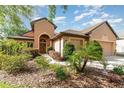 Exterior view features lush landscaping leading to a home with a covered entrance and a two-car garage at 3048 New Haven Pl, Mount Dora, FL 32757