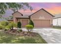 Home exterior showcases a spacious driveway leading to a two-car garage, enhanced by manicured landscaping at 3048 New Haven Pl, Mount Dora, FL 32757