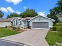 Charming one-story home with beautiful landscaping, lush lawn, and a screened two-car garage on a sunny day at 4717 Inverness Dr, Leesburg, FL 34748