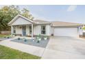 Charming single-Gathering home featuring a blue front door, an attached garage, and nicely landscaped front yard at 548 E Belt Ave, Bushnell, FL 33513