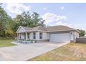 Charming single-Gathering home featuring a blue front door, an attached garage, and nicely landscaped front yard at 548 E Belt Ave, Bushnell, FL 33513