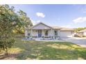 Charming single-Gathering home featuring a blue front door, an attached garage, and nicely landscaped front yard at 548 E Belt Ave, Bushnell, FL 33513