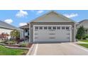 Exterior view of the single Gathering home showing two-car garage with decorative carriage hardware at 5702 Grimes Ct, The Villages, FL 32163