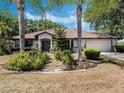 Well-maintained single-story home with a lush front yard featuring decorative rock landscaping and palm trees at 5906 Prince Philip Ct, Leesburg, FL 34748