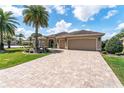Beautiful home featuring a paver driveway, lush lawn, and well-maintained landscaping at 630 Laurel Run, The Villages, FL 32162