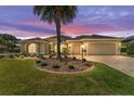 Inviting home with a well-manicured lawn, charming landscaping, and a convenient two-car garage at dusk at 630 Laurel Run, The Villages, FL 32162