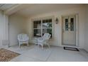 Cozy front porch featuring white wicker furniture, a decorative door, and a welcoming ambiance at 725 Beldon Ct, The Villages, FL 32162
