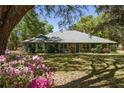 Landscaped front yard featuring mature trees, a well-manicured lawn, and a charming one-story home at 10159 Se 174Th St, Summerfield, FL 34491