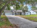 Charming single-story home with a long driveway, well-manicured lawn, a palm tree, and an attached garage at 10323 Joanies Run, Leesburg, FL 34788