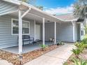 Inviting covered front porch featuring a bench, landscaping, and a clear view of the house number at 10323 Joanies Run, Leesburg, FL 34788