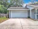 A spacious two-car garage with a concrete driveway, complemented by the home's charming exterior at 10323 Joanies Run, Leesburg, FL 34788