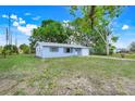 Quaint single-story home featuring a lush green lawn, large trees, and an attached garage at 1109 Hampton St, Clermont, FL 34711