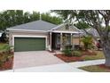 Inviting single-Gathering home with a covered porch, attached garage, and a brick-paved driveway, adding to its charm at 135 Crepe Myrtle Dr, Groveland, FL 34736