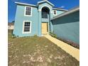 Light blue, two-story home with a yellow front door and well-kept lawn at 1420 Kissimmee Ct, Kissimmee, FL 34759