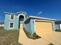 Light blue home boasting a yellow garage door, light-colored trim and lush front lawn at 1420 Kissimmee Ct, Kissimmee, FL 34759