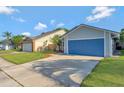 Spacious driveway leading to a blue garage door, set against a well-kept lawn at 1566 Lawndale Cir, Winter Park, FL 32792