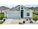 Charming single-Gathering home featuring a well-manicured lawn, light blue exterior, and attached two-car garage at 1966 Wallingford Loop, Mount Dora, FL 32757
