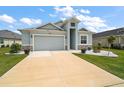 Inviting single-Gathering home with a well-manicured lawn, light blue exterior, and an attached two-car garage at 1966 Wallingford Loop, Mount Dora, FL 32757