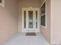Close-up of a decorative front door with sidelights, a welcome mat, and neutral paint at 26301 Sackamaxon Dr, Sorrento, FL 32776