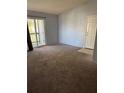 Spacious living room featuring neutral carpet, sliding glass doors to the balcony, and a white front door at 3748 Idlebrook Cir # 202, Casselberry, FL 32707