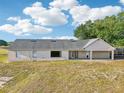 Exterior rear view of home with light-colored walls, a dark roof, and a lush lawn at 4635 Brantley Rd, Groveland, FL 34736