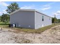 A view of the home's gray vinyl siding and the AC unit on a grassy patch at 48 Oakridge Dr, Frostproof, FL 33843