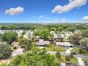 Aerial view of a residential neighborhood with mature trees, blue skies and scattered clouds at 515 Scenic St, Leesburg, FL 34748
