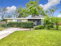 Charming single-story home with green lawn, mature trees and a screened porch at 515 Scenic St, Leesburg, FL 34748