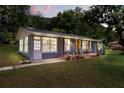 Charming home features a cozy front porch, large windows, and is surrounded by lush greenery at 7115 Lake Ola Dr, Mount Dora, FL 32757