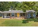 Inviting single-story home featuring a bright yellow door, large windows, and a cozy front porch at 7115 Lake Ola Dr, Mount Dora, FL 32757