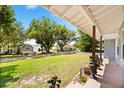 Expansive front porch view of a lush green lawn, lake, and neighboring houses in a serene setting at 7115 Lake Ola Dr, Mount Dora, FL 32757