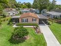 Inviting single-story home featuring a well-manicured lawn, mature landscaping and a screened in porch at 1003 Parker Pl, Lady Lake, FL 32159