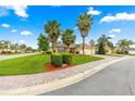 Single-story home boasts a brick-paved driveway, mature palm trees, green lawn, and tasteful landscaping at 10460 Silver Maple Ave, Oxford, FL 34484
