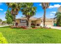 Well-maintained single-story home features lush green lawn, beautiful palms, brick paved driveway, and stone accents at 10460 Silver Maple Ave, Oxford, FL 34484