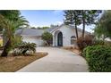 Inviting single-story home featuring a concrete driveway, arched entryway, attached garage, and mature landscaping at 11024 Windchime Cir, Clermont, FL 34711
