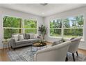 Bright living room with large windows offering picturesque views, stylish furnishings, and hardwood floors at 1415 S Baton Dr, Deltona, FL 32725