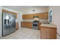Open kitchen with stainless steel appliances, wood cabinets and bright tile flooring at 15918 Summit Ct, Clermont, FL 34711
