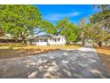 Long driveway leading to a charming single-story home, framed by lush trees on an expansive lot at 16724 Highland Ave, Montverde, FL 34756