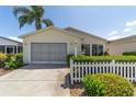 Exterior of a single-story home with a screened garage, well-kept landscaping, and a white picket fence at 1706 Moreno Pl, The Villages, FL 32159