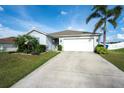 Inviting single-story home with a spacious driveway, manicured lawn, and lush tropical landscaping at 2256 Gladiolus Ln, Mascotte, FL 34753