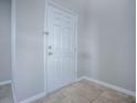 A bright entryway showcases a white paneled front door and neutral-toned tile flooring for a clean and welcoming entrance at 34107 Alameda Dr, Sorrento, FL 32776