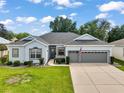 Inviting single-story home with an attached two-car garage and manicured front yard at 3800 Woodleaf Ct, Leesburg, FL 34748