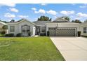 Charming single-story home with a well-manicured lawn, two-car garage, and welcoming facade at 3800 Woodleaf Ct, Leesburg, FL 34748