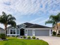 Attractive single-story house featuring a three-car garage, complemented by lush green lawns and swaying palm trees at 3942 Zenith Loop, The Villages, FL 32163