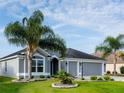 Lovely single-story home with a three-car garage, manicured lawn, and tropical palm trees against a blue sky at 3942 Zenith Loop, The Villages, FL 32163