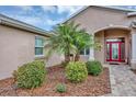 Welcoming front entrance with a vibrant red door, complemented by decorative landscaping and manicured shrubbery at 4247 James River Cir, Leesburg, FL 34748