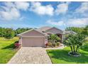 Charming home featuring a well-maintained lawn, mature palm trees, and a brick driveway, enhancing its curb appeal at 4247 James River Cir, Leesburg, FL 34748