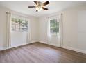 Bright bedroom with wood-look floors, neutral walls, two windows, and modern ceiling fan at 425 Marion Oaks Dr, Ocala, FL 34473
