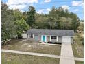 View of the single-story home with gray siding, white trim, manicured front yard, and inviting blue door at 425 Marion Oaks Dr, Ocala, FL 34473