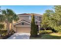 Charming two-story home showcasing a well-manicured lawn, mature trees, and a spacious two-car garage at 4328 Acorn Ct, Davenport, FL 33837